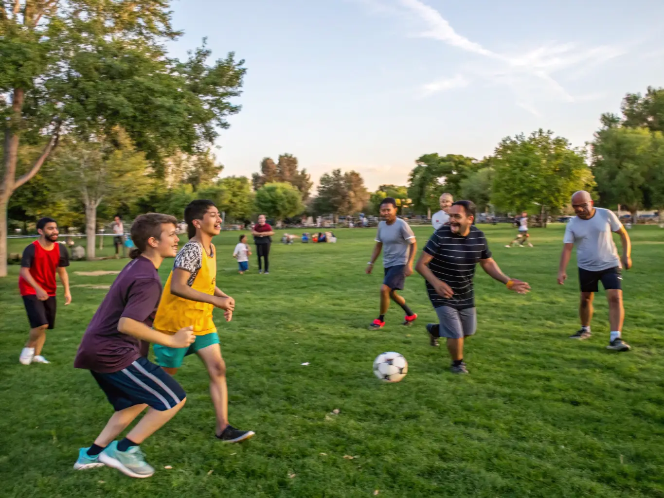 A vibrant image of children and adults engaging in a soccer match in a local park, smiling and enjoying the activity, representing the Community Sports Programs.